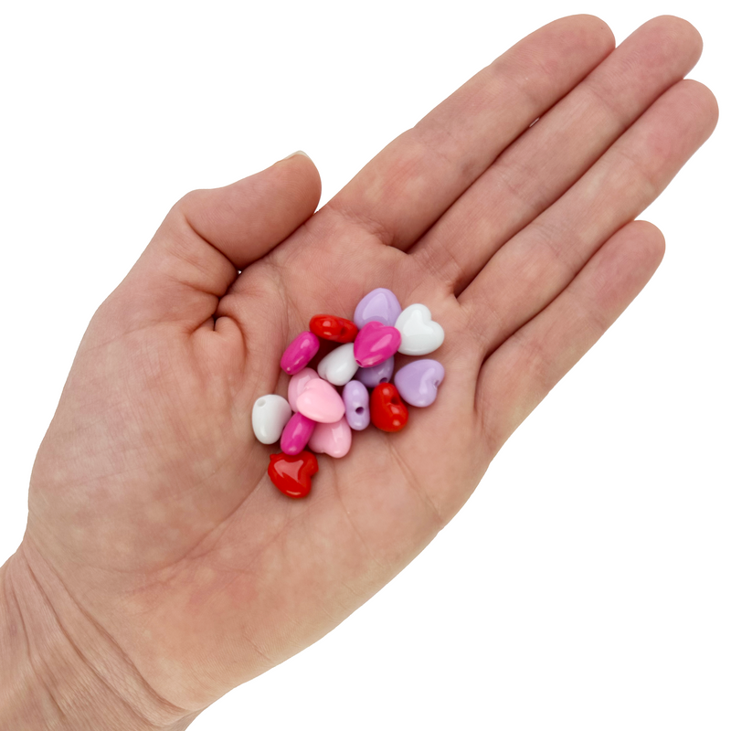Assorted 10mm heart-shaped acrylic beads in red, pink, purple and white colors in a hand on a white background