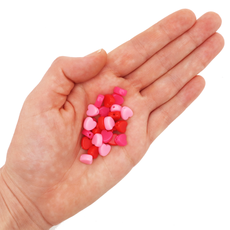 Assorted 8mm heart-shaped acrylic beads in red and pink colors on a hand on a white background