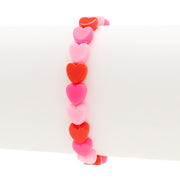 Assorted 8mm heart-shaped acrylic beads in red and pink colors on a white bracelet mandrel on a white background